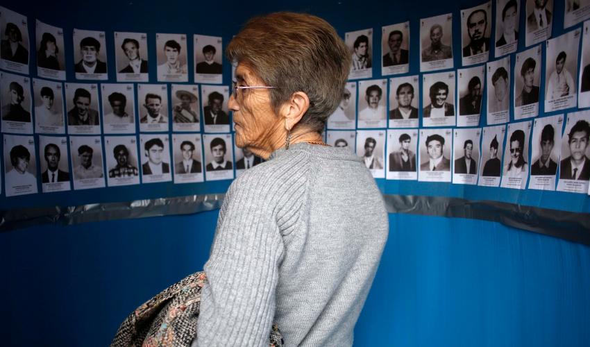 Mujer observa retratos de los 70 Detenidos Desaparecidos y Ejecutados Políticos de Paine 